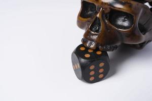 Creative composition of a skull and a dice, a skull bites a dice, on a white background, space for copying photo