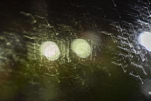 Night unfocused view through wet glass with raindrops on the background of street lights, blurred background photo