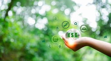 ESG icon concept in hand for environmental, social and governance in sustainable and ethical business on Network connection on green background. Ideas for production and conservation of environment. photo