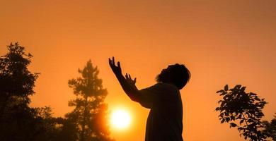 Worship with faith of christian concept. Spiritual prayer hands over sunshine with blurred beautiful sunrise sunset background. Preacher pray to God in morning with devotion. Christian man have hope. photo