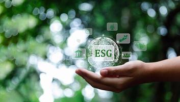 ESG icon concept in hand for environmental, social and governance in sustainable and ethical business on Network connection on green background. Ideas for production and conservation of environment. photo