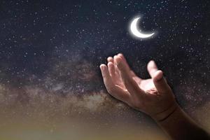 el hombre de la mano musulmán reza en la oscuridad con el fondo del cielo lunar, el culto masculino a dios con fe y creencia en el hombre negro, árabe musulmán rezando por la bendición de alá con esperanza. concepto religión islam. foto