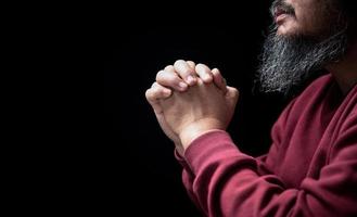 Hands folded in prayer on in church concept for faith, spirituality and religion, man praying in the morning. man hand with praying god. Person Christian men who have faith in Jesus worship in dark. photo