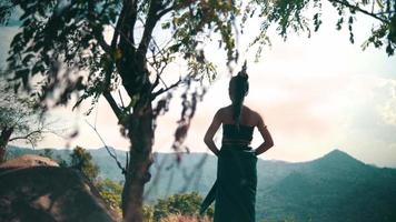asiatico donna con un' lungo vestito e nero capelli in piedi nel davanti di il canyon per godere il Visualizza a partire dal il superiore di il montagna video