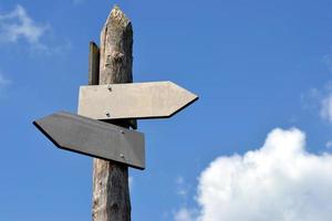 Wooden Signpost with Two Arrows and Sky in Background photo