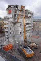 máquina de demolición y desmantelamiento en acción con edificio de varios pisos foto