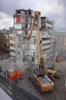 máquina de demolición y desmantelamiento en acción con edificio de varios pisos foto