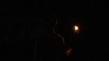 un' musulmano ragazzo a piedi nel il notte mentre Tenere il fuoco torcia solo per leggero il modo video