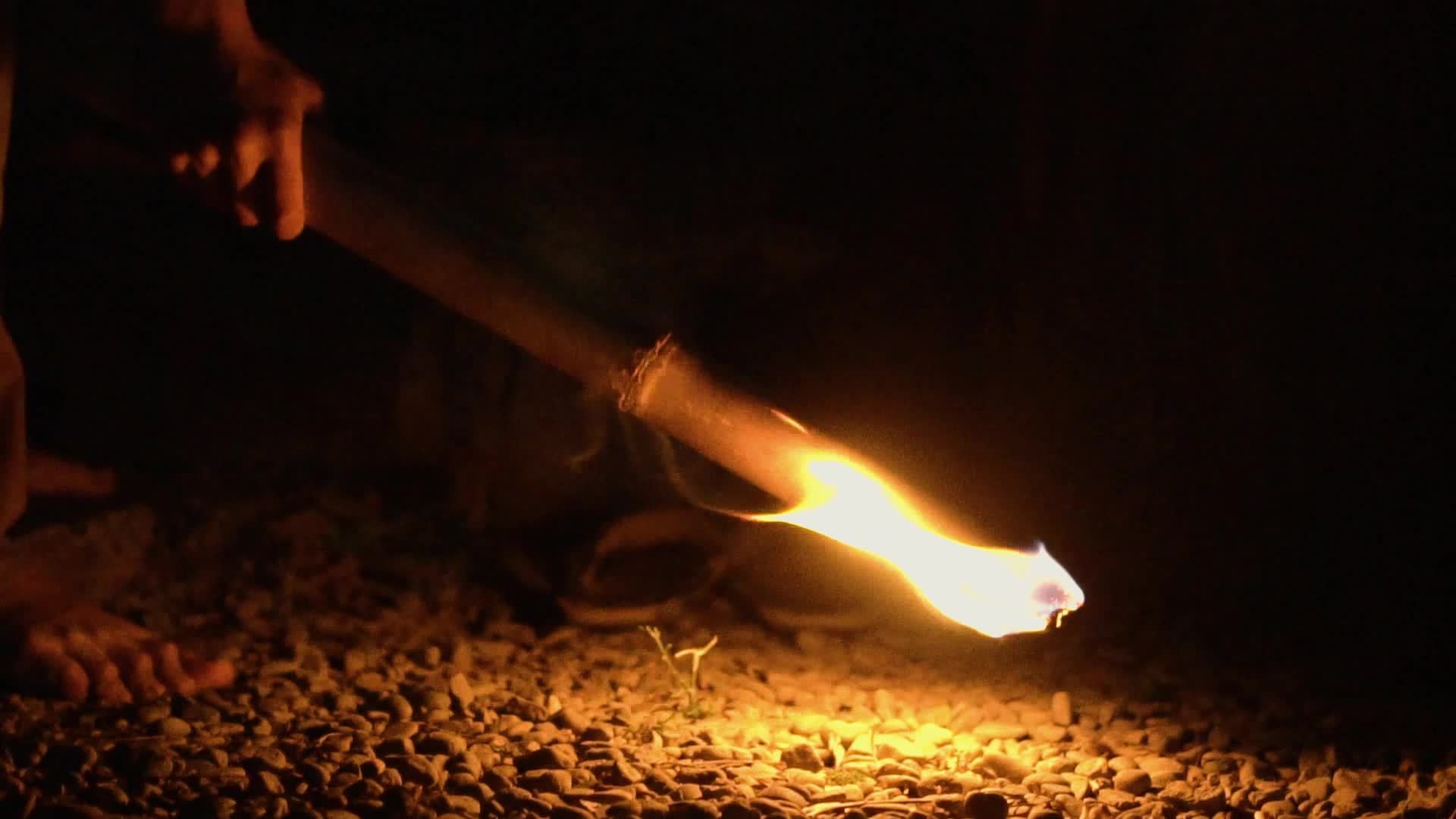 A Flame from the fire torch made by a bamboo stick brightens in the