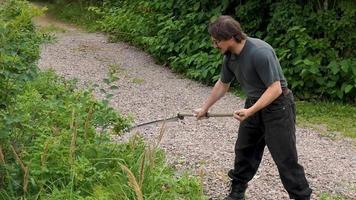 en man klipper de gräs med en hand lie. klippa de gräs med ett gammal lie. de jordbrukare traditionellt klipper de gräsmatta. de gräsklippare klipper de grön gräs med en manuell metall lie. video