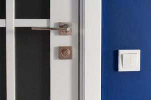 White interior door with handle. Blue wall in modern apartment photo