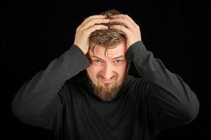 Overworking, head pain concept. Young guy in black polo neck sweater. photo