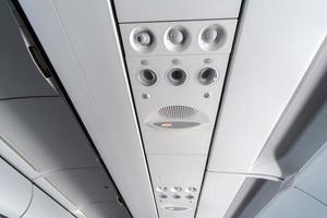 Airplane air conditioning control panel over seats. Stuffy air in aircraft cabin with people. New low-cost airline photo