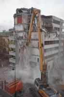 máquina de demolición y desmantelamiento en acción con edificio de varios pisos foto