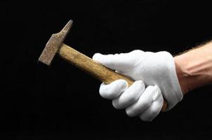 Hand holding a hammer on black background photo