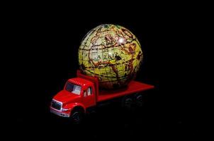 Toy truck carrying a globe on black background photo