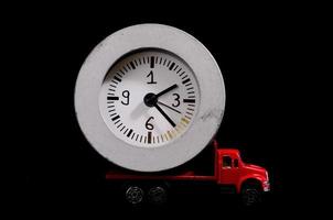 Toy truck carrying a clock on black background photo