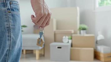 Moving house, relocation. Man hold key house keychain in new apartment, inside the room was a cardboard box containing personal belongings and furniture. move in the apartment or condominium video