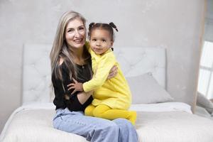 Multi-ethnic mom and daughter. Cheerful mother hugs her daughter of African nationality. Family from different races. photo