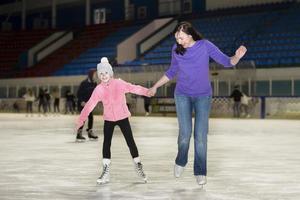 Mom and daughter are skating on the ice arena. photo