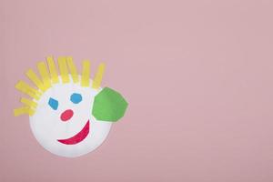 Paper crafts for children. Application of children's creativity. Kindergarten and craft school. On a pink background, a funny face of a man made of colored paper. photo