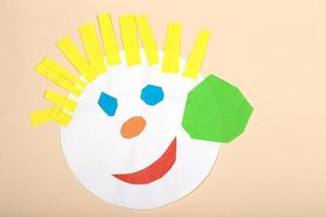 Paper crafts for children. Application of children's creativity. Kindergarten and craft school. On a beige background, a funny face of a man made of colored paper. photo