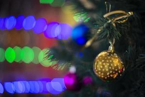 Golden Christmas ball on the Christmas tree against the background of multi-colored bokeh. photo