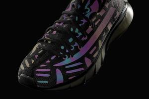 Part of a black trainer with reflective details on a black background. Sport shoes. Sports or jogging.