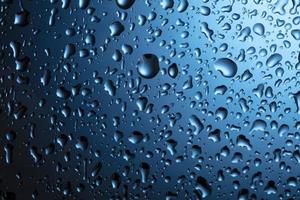 Water drops close-up on a blue glass background. photo