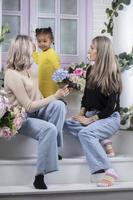 Family from different races. Mom grandmother fair-skinned and a little African American girl play on the doorstep of the house. photo