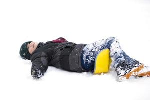 Child in winter. The boy fell on the sled and lies in the snow. photo