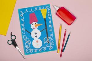 manualidades de papel navideñas para niños. aplicación de la creatividad infantil. jardín de infantes y escuela de manualidades. sobre un fondo beige, un muñeco de nieve hecho de papel de colores. foto