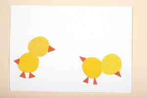 Paper crafts for children. Application of children's creativity. Kindergarten and craft school. On a beige background made of colored paper chickens.