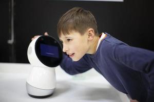 niño hablando, jugando con un robot androide en la exposición foto