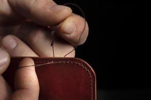 Making leather wallets. The hands of the master sew a leather product. photo