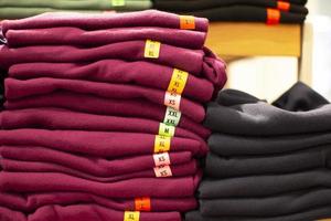 The store has stacks of sweaters with sizes listed for sale. photo