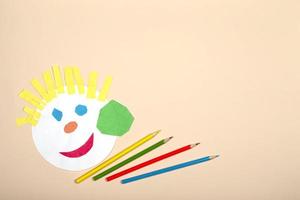 Paper crafts for children. Application of children's creativity. Kindergarten and craft school. On a beige background, a funny face of a man made of colored paper. photo