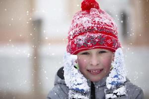 Child in winter. A little boy in a warm hat and mittens looks at the camera and smiles. photo