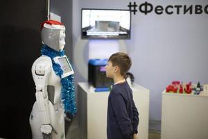 Belarus, city of Gomel, January 11, 2022. Robot Festival. Boy talking, playing with android robot at the exhibition photo