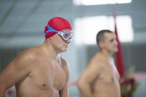 Belarus, city of Gomel, September 03, 2021. City sports pool.A male swimmer in a swimming cap and goggles on the background of the pool. photo