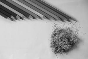 colored pencils neatly lined up on white paper, there are sharpeners and leaves photo