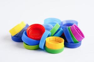 tapas de botellas de plástico de colores para reciclar sobre fondo blanco. foto