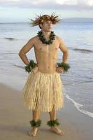 Male hula dancer poses with hand on hips at sunset by the beach. photo
