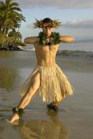 This Hawaiian Hula Dancer hits a strength pose and showing off his muscular leg on the beach in Maui, Hawaii photo