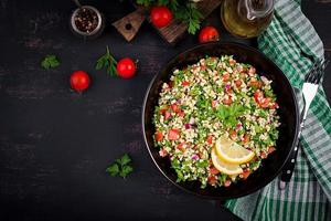 Tabbouleh salad. Traditional middle eastern or arab dish. Levantine vegetarian salad with parsley, mint, bulgur, tomato. Top view photo