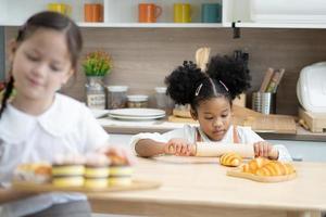 dos niños pequeños felices cocinando juntos, sacando masa, parados en una encimera de madera en una cocina moderna, lindos caseros