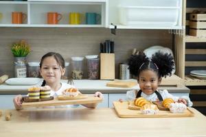 dos niños pequeños felices cocinando juntos, sacando masa, parados en una encimera de madera en una cocina moderna, lindos caseros