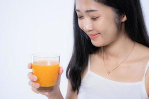 Beautiful asian woman drinking orange juice, healthcare, skin, beauty and wellbeing concepts, isolated on white background photo