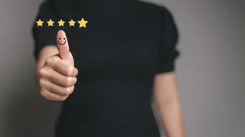 Customer satisfaction concept. Hand with thumb up Positive emotion smiley face icon and five star with copy space. photo