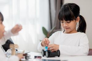 Asia students learn at home in coding robot cars and electronic board cables in STEM, STEAM, mathematics engineering science technology computer code in robotics for kids concept. photo